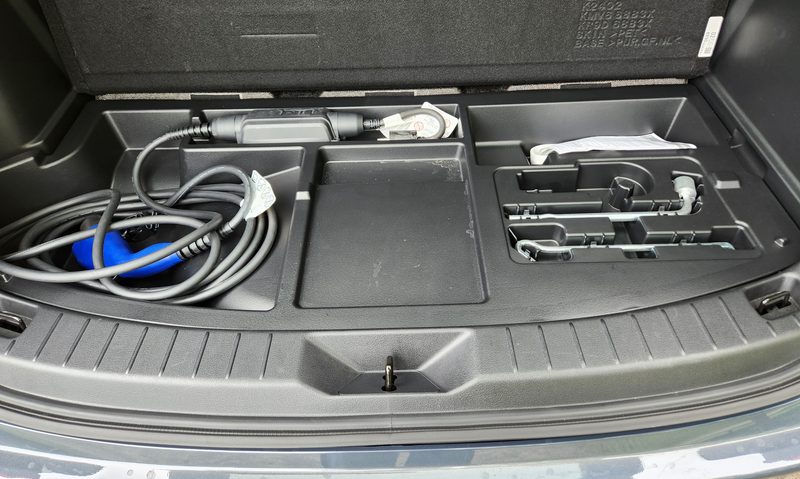 2025 Mazda CX-70 PHEV interior view of cargo space storage for charging cable and adapter under mat.