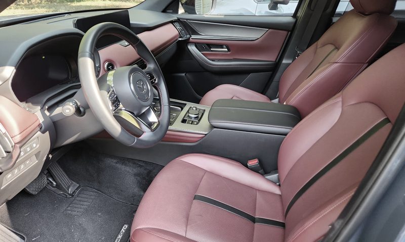 2025 Mazda CX-70 PHEV interior view of front seats, console, and dashboard taken from open driver side door.