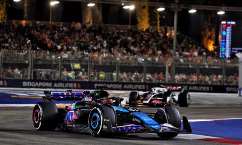 Alpine F1 race car in the 2024 F1 Singapore Grand Prix with spectator grandstands in the background.