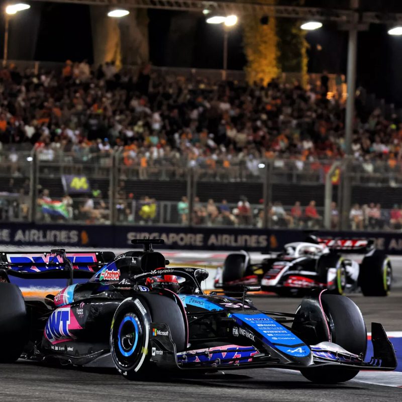 Alpine F1 race car in the 2024 F1 Singapore Grand Prix with spectator grandstands in the background.