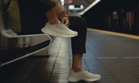 person tying shoe in subway