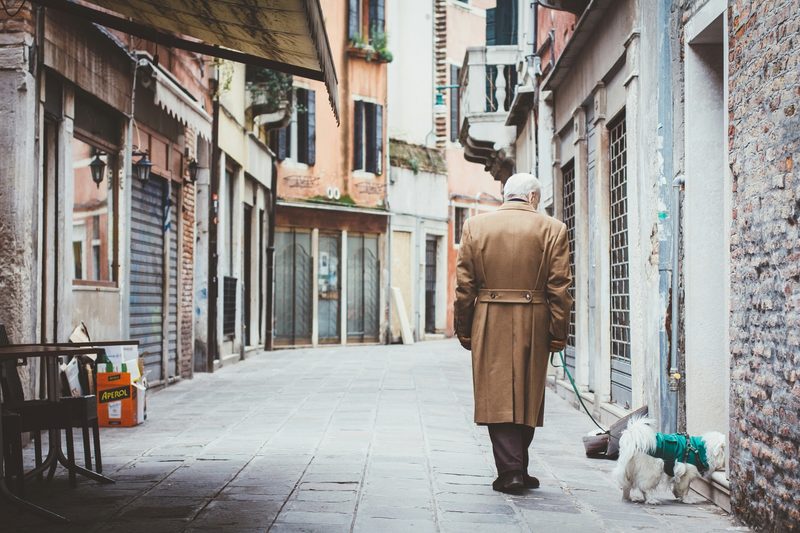 Man in trench coat walking a dog