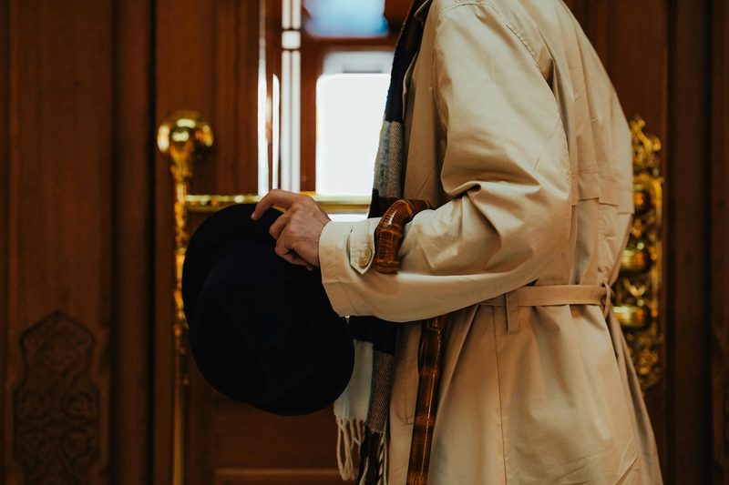 Man in trench coat with umbrella and hat