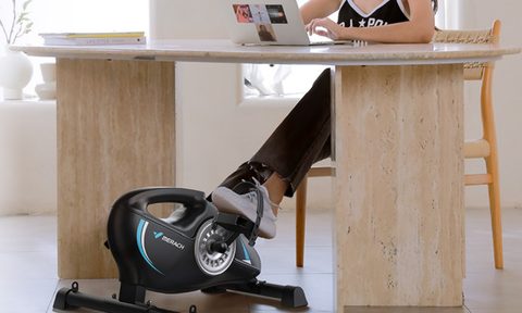 A woman using the Merach Under Desk Bike.