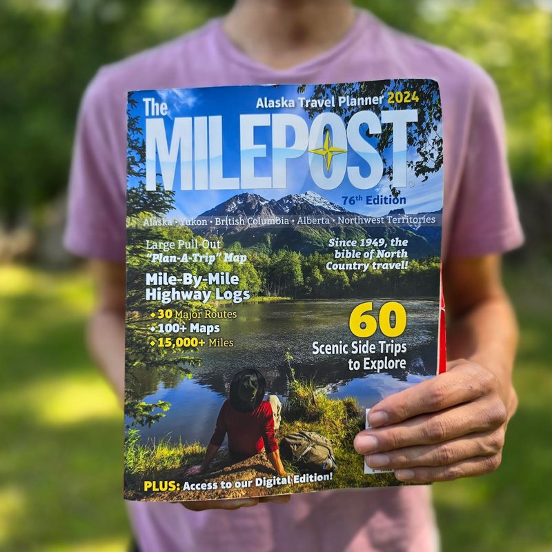 A man holding the Milepost magazine outdoors