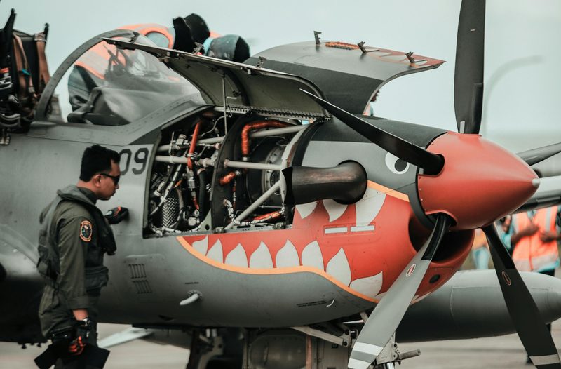 Pilot next to plane w engine showing