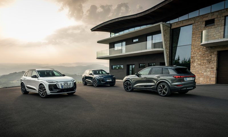 Three Audi Q6 e-trons parked in front of a modern residence.