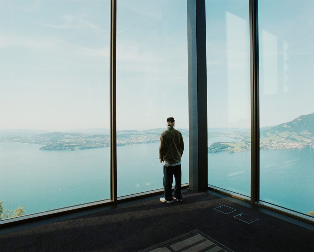 man overlooking Swiss Alps in front of tall window
