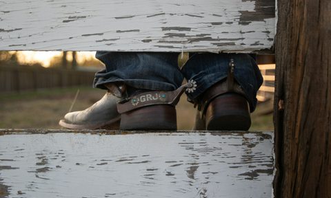 cowboy boots sitting on top of fence