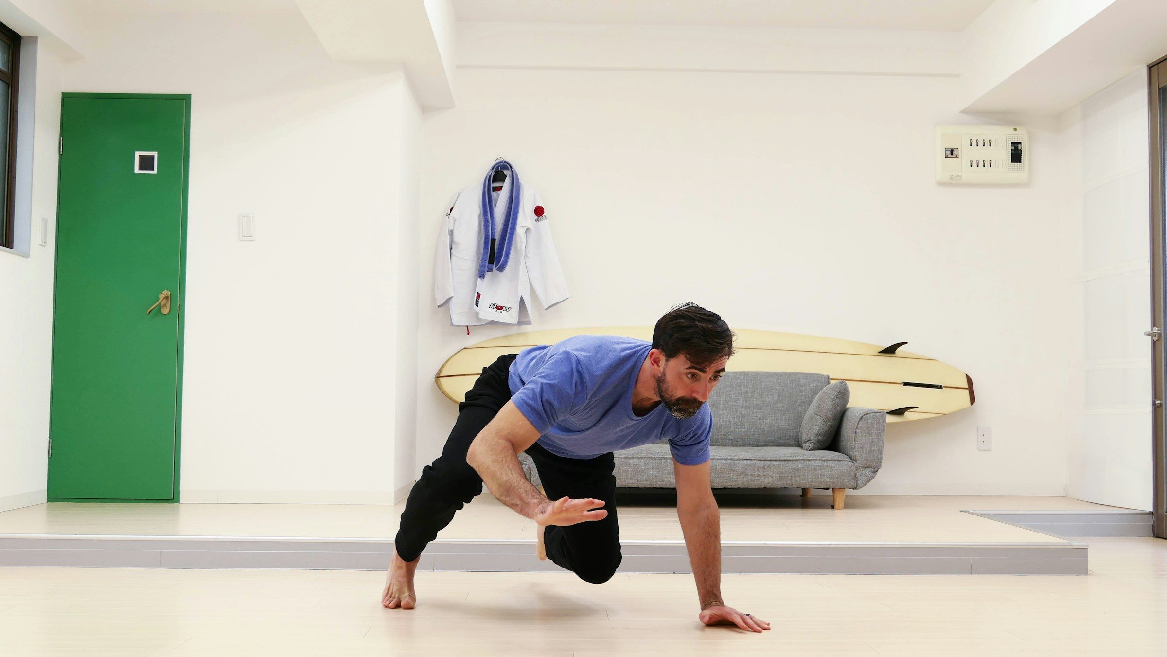 man doing bear crawl in room grey couch in background