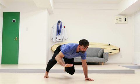man doing bear crawl in room grey couch in background