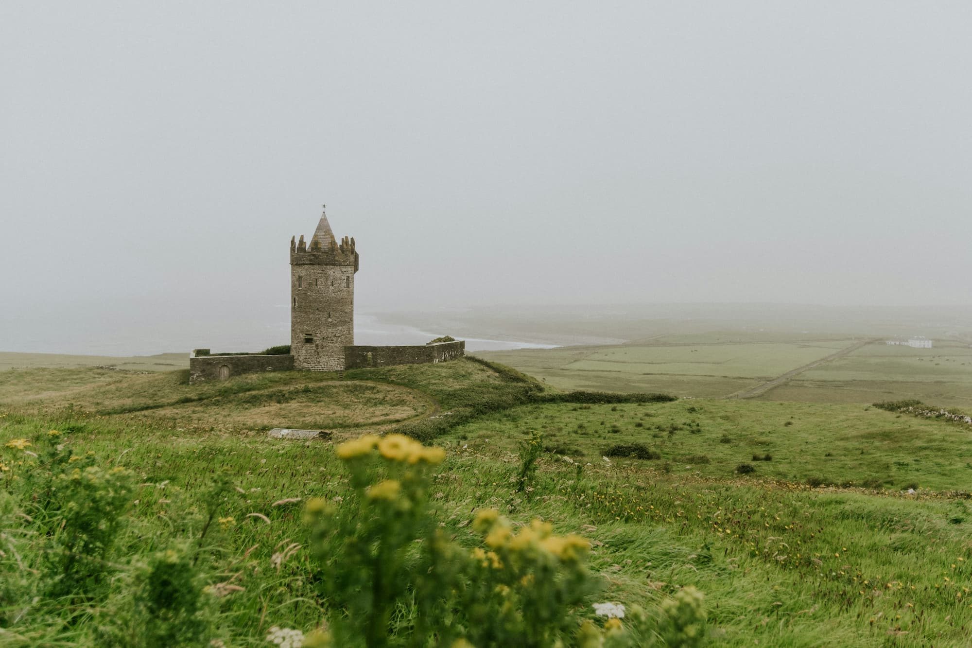 Castle in fog surrounded by green rolling hills in Ireland
