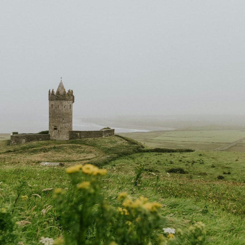 Castle in fog surrounded by green rolling hills in Ireland