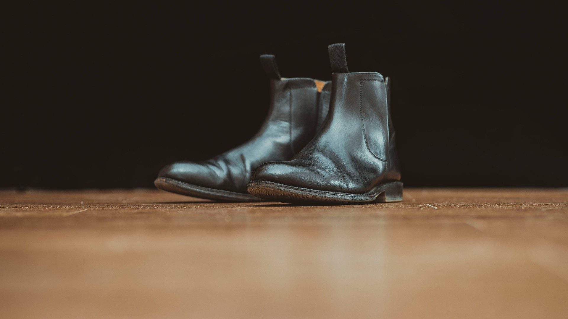 black chelsea boots sitting on wood floor