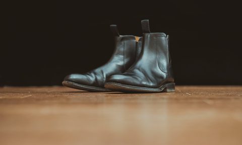 black chelsea boots sitting on wood floor