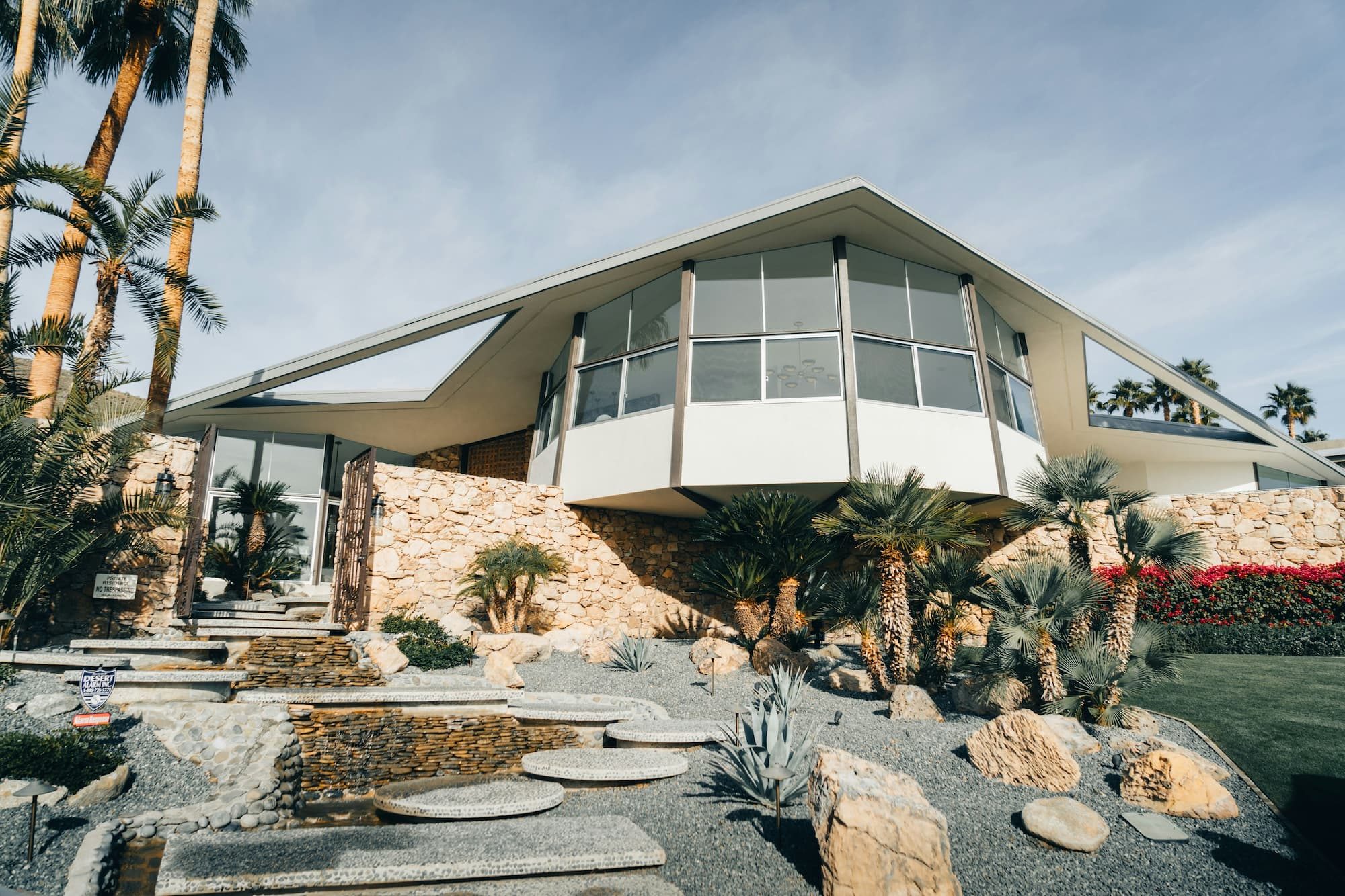 a mid century modern house with palm trees and landscaping