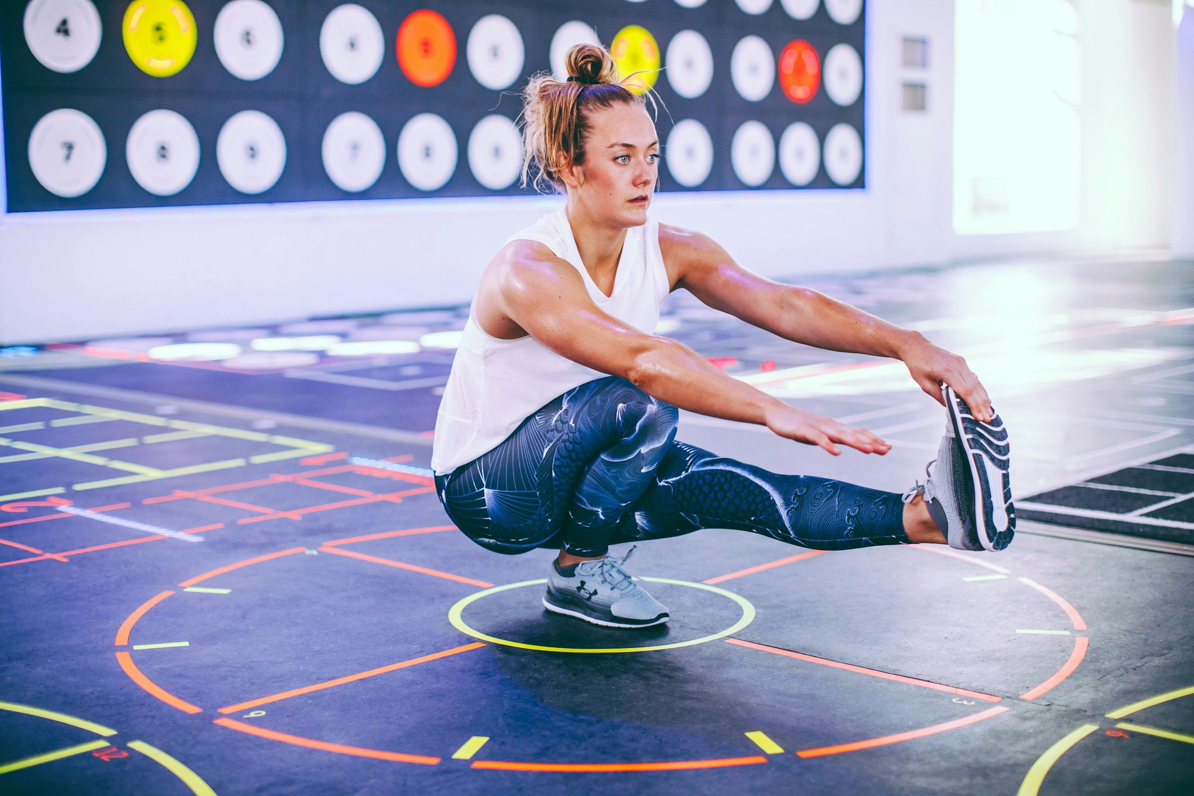 woman doing pistol squat exercise inside gym single leg squat