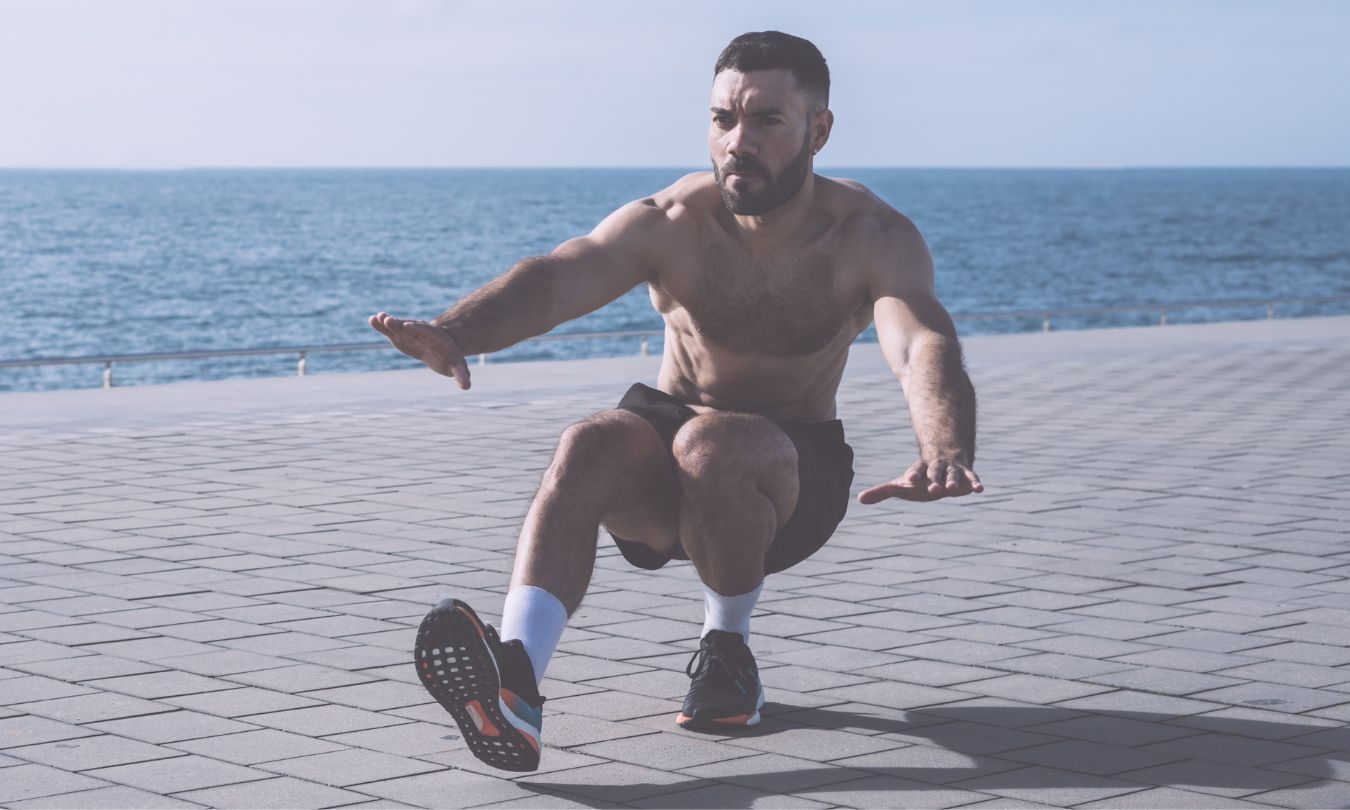 man doing pistol squats by the water