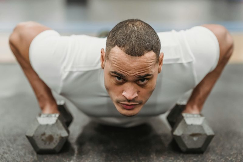 man wearing white shirt doing dumbbell renegade row