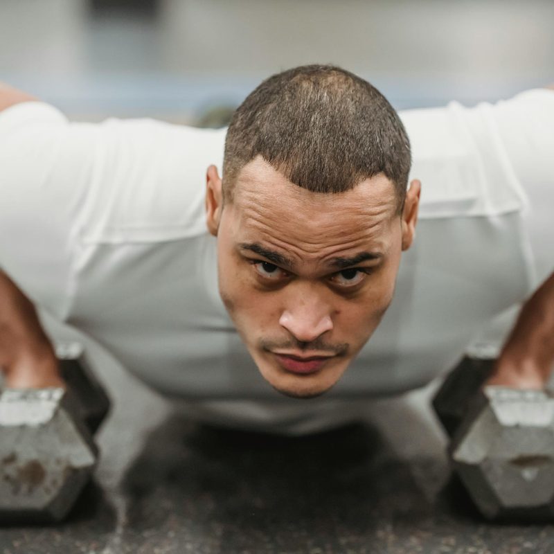 man wearing white shirt doing dumbbell renegade row