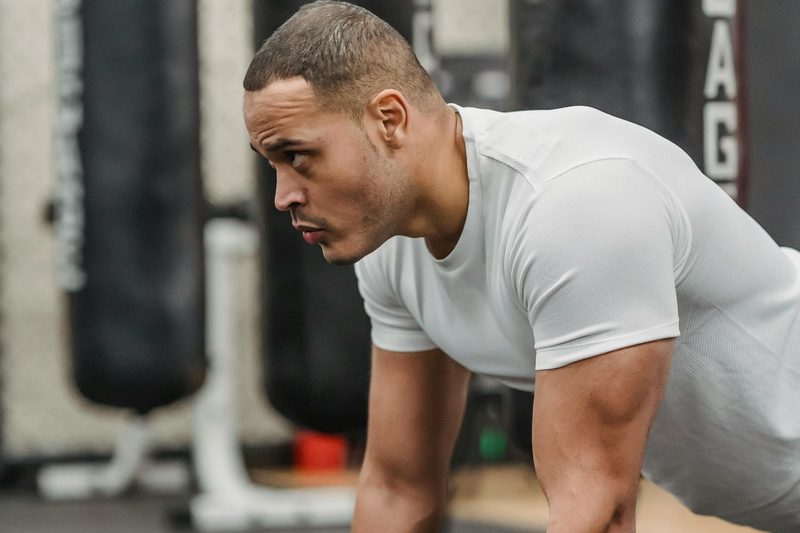 side view of man white shirt doing renegade dumbbell row