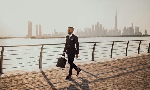 Busy business man walking by the water in a business suit with sunglasses dressed sharp