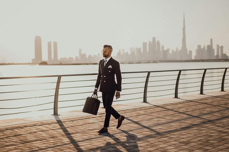 Busy business man walking by the water in a business suit with sunglasses dressed sharp