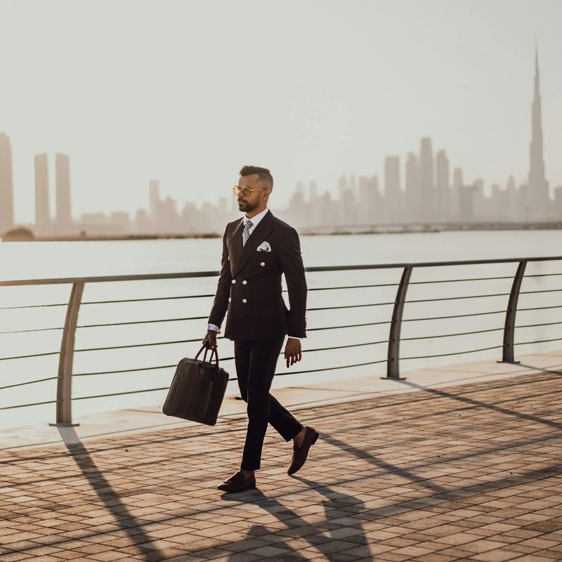 Busy business man walking by the water in a business suit with sunglasses dressed sharp