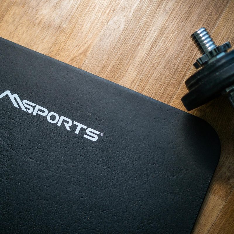 Close-up of black gym mat and dumbbell on wooden floor