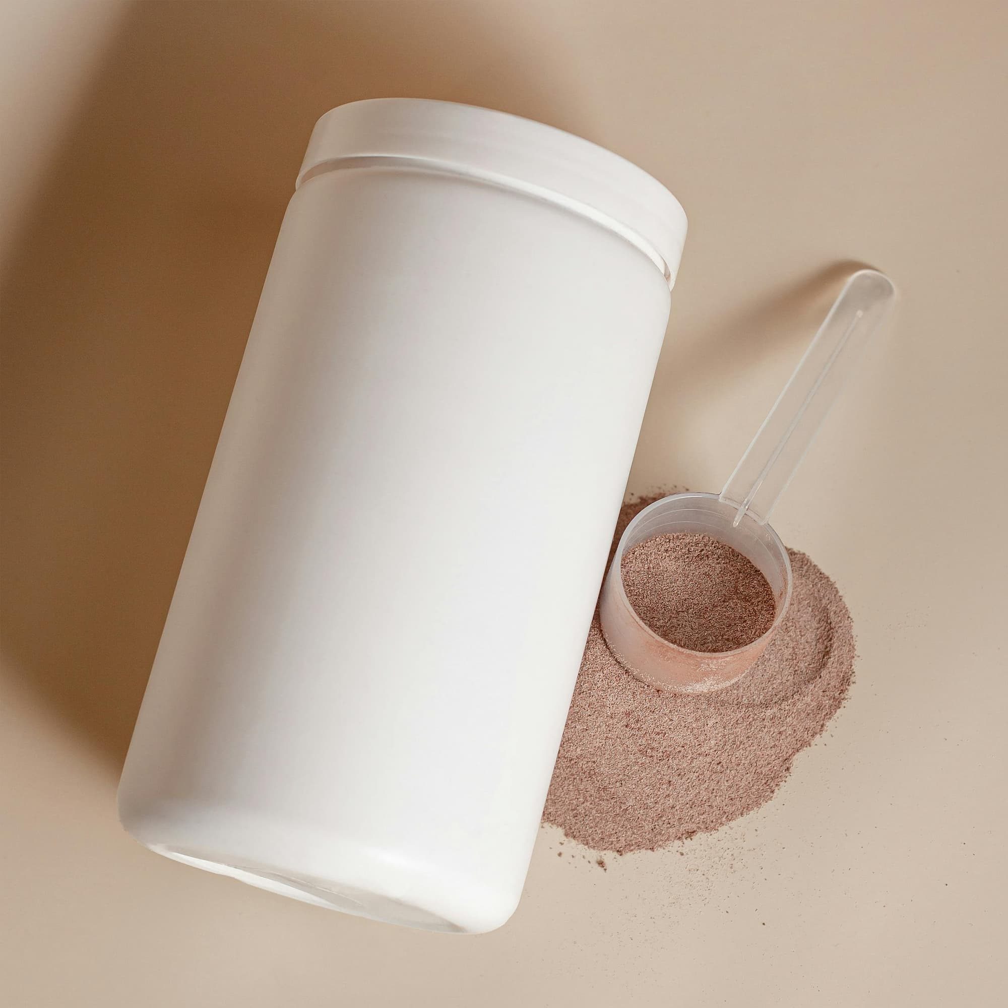 scoop of brown powder next to a white container