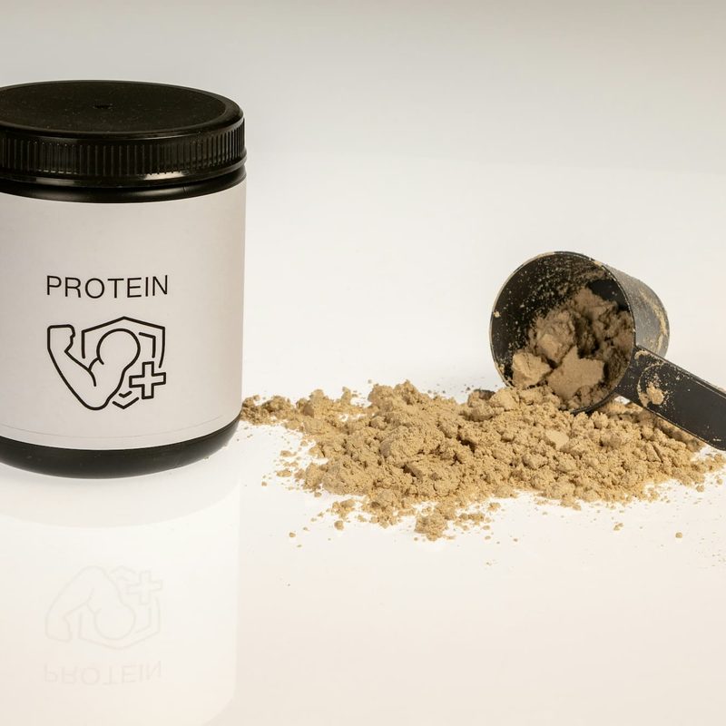 A jar of protein powder next to a scoop of protein powder
