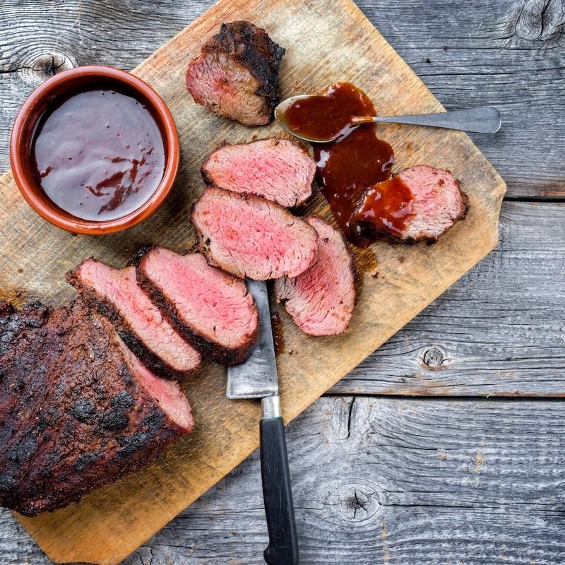 Barbecue dry-aged wagyu tri-tip steak with BBQ sauce as dip as top view on a wooden cutting board