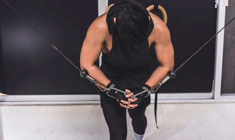 Man black shirt doing cable crossover on cable machine indoors