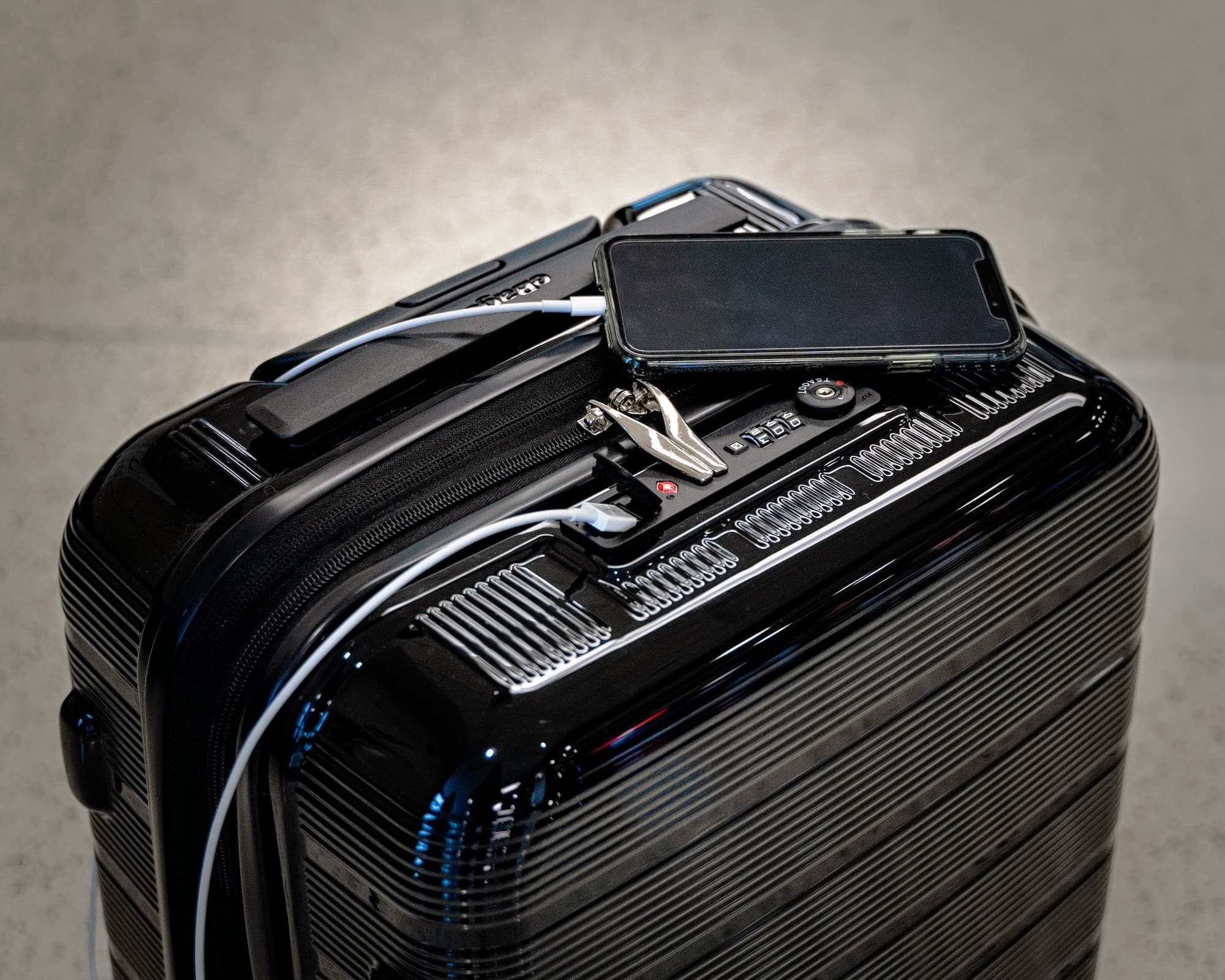 shiny black suitcase with phone on top