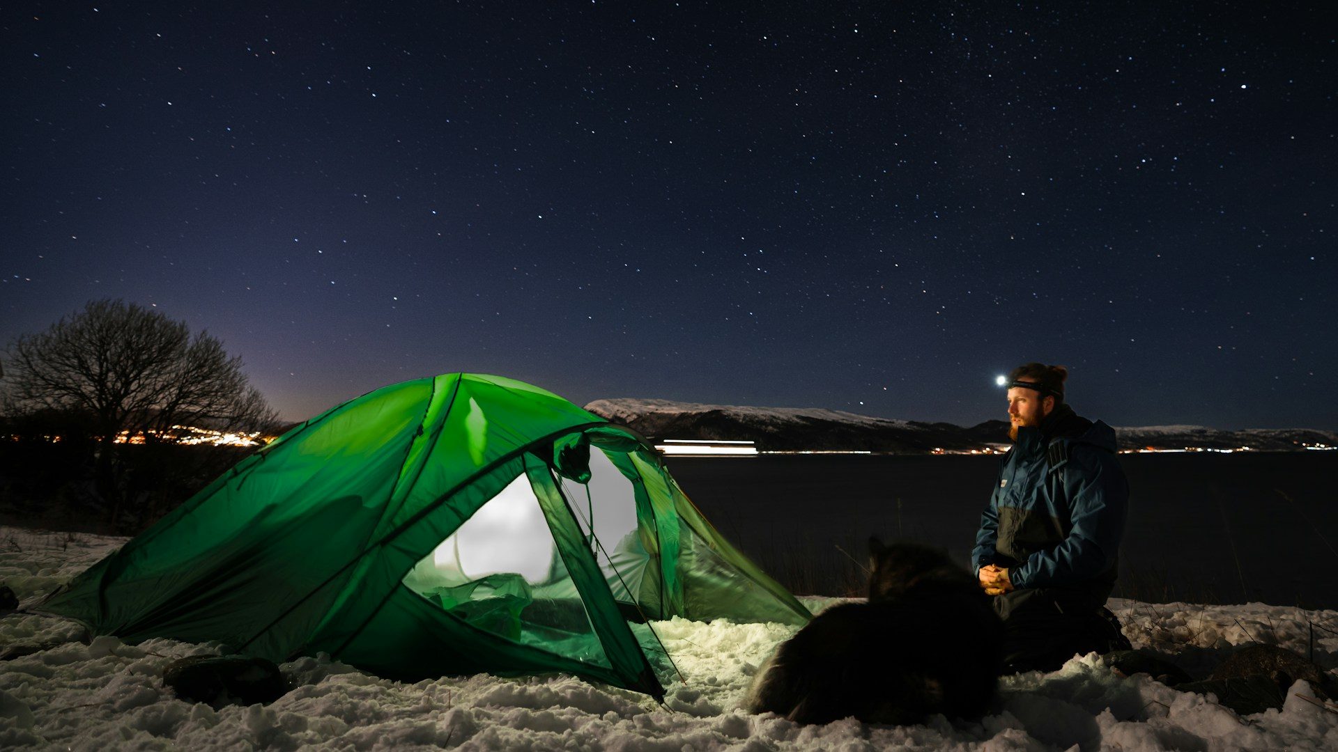 Man winter camping with a green tent