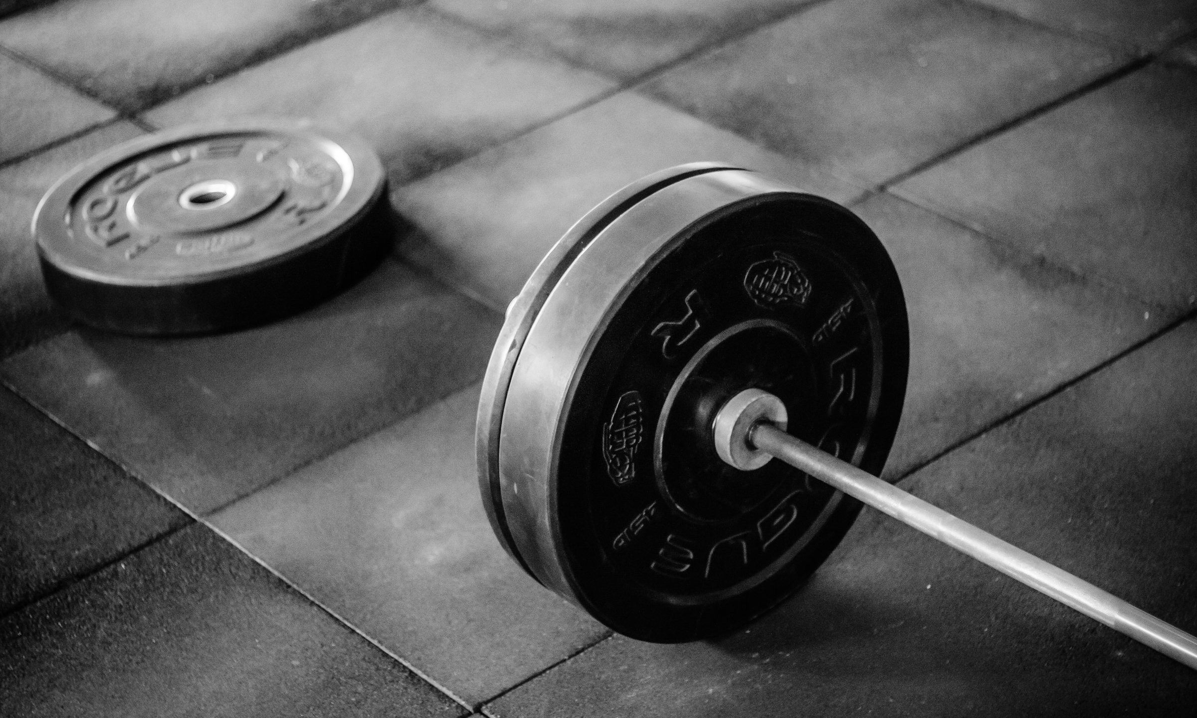 barbell on floor on black floor in gym with weights close up