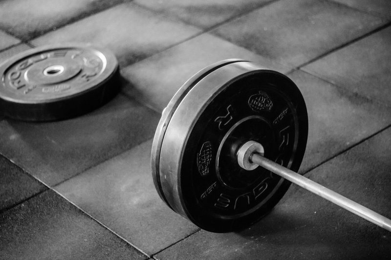 barbell on floor on black floor in gym with weights close up