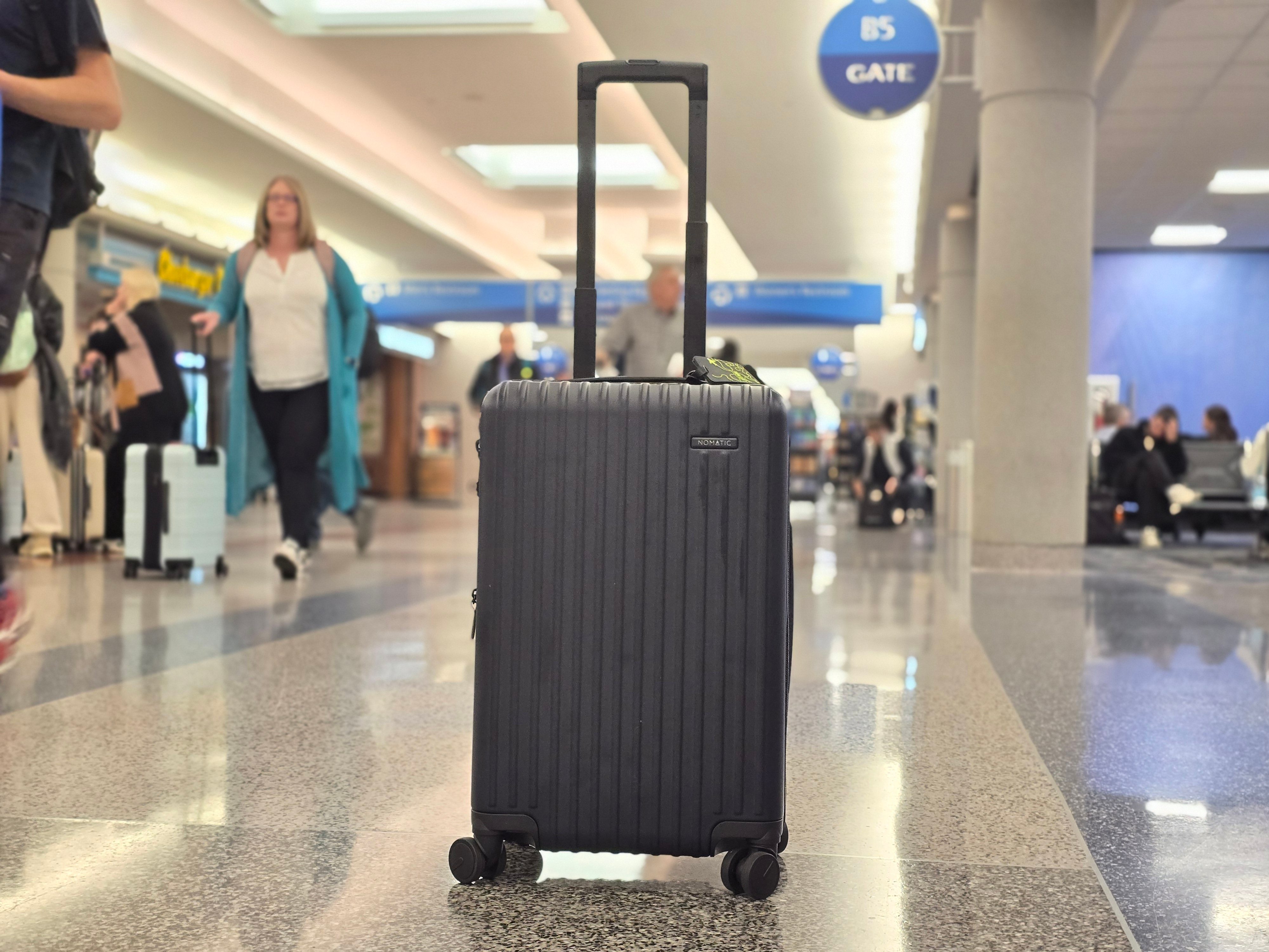 A nomatic carry on bag standing alone in an airport