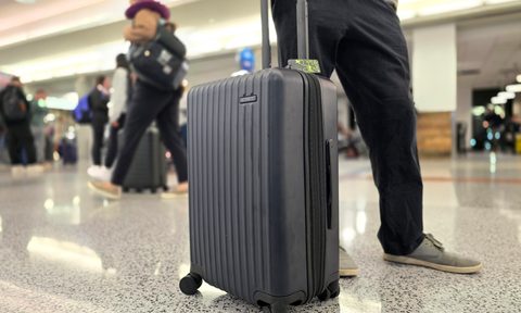 A man holding the handle of a nomatic bag in the airport