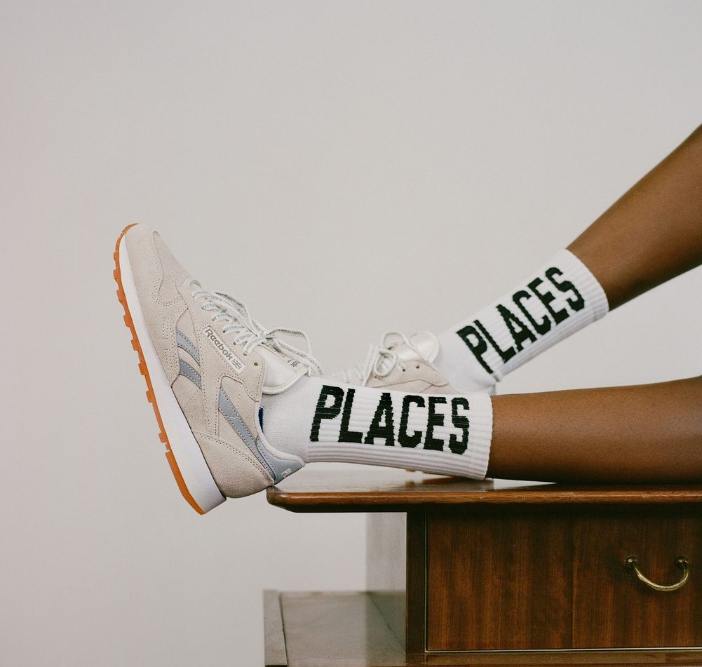 model sitting on desk with white sneakers and high socks
