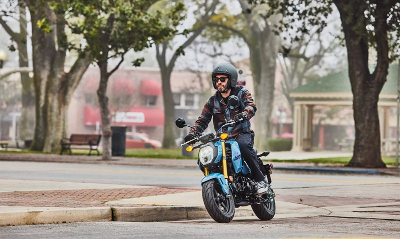 A person coming around a city street corner on on a 2025 Honda Grom.
