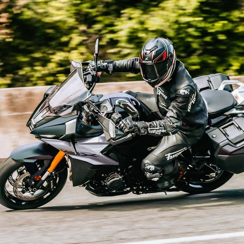 A person riding a Suzuki 2024 GSX-S1000GX+on a highway left profile view