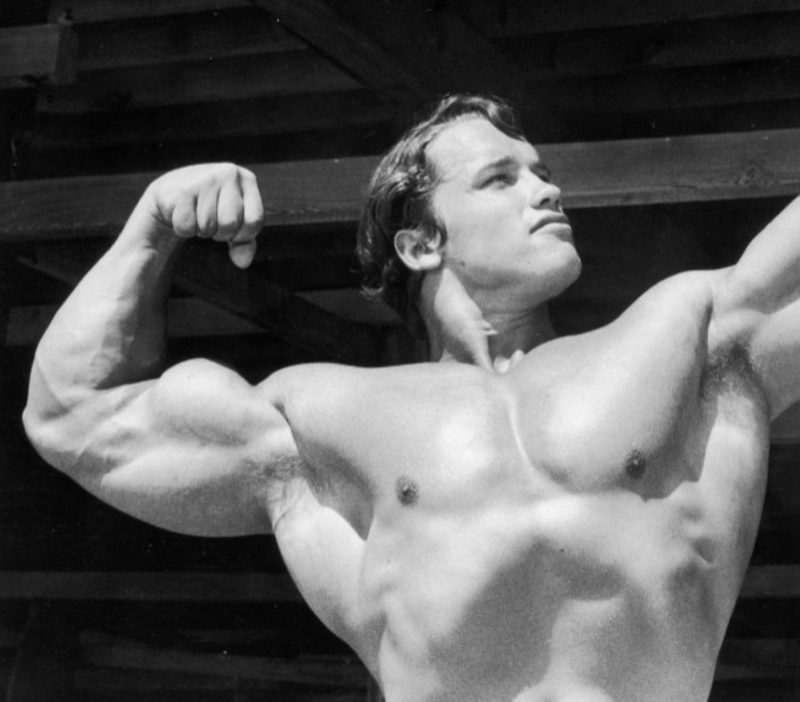 Arnold flexing shirtless black and white pic Getty
