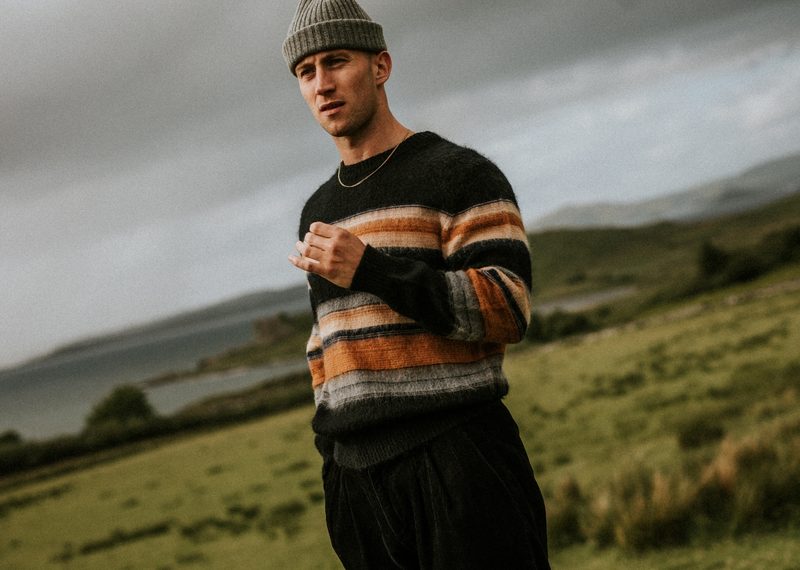 Man in a field wearing a sweater and beanie