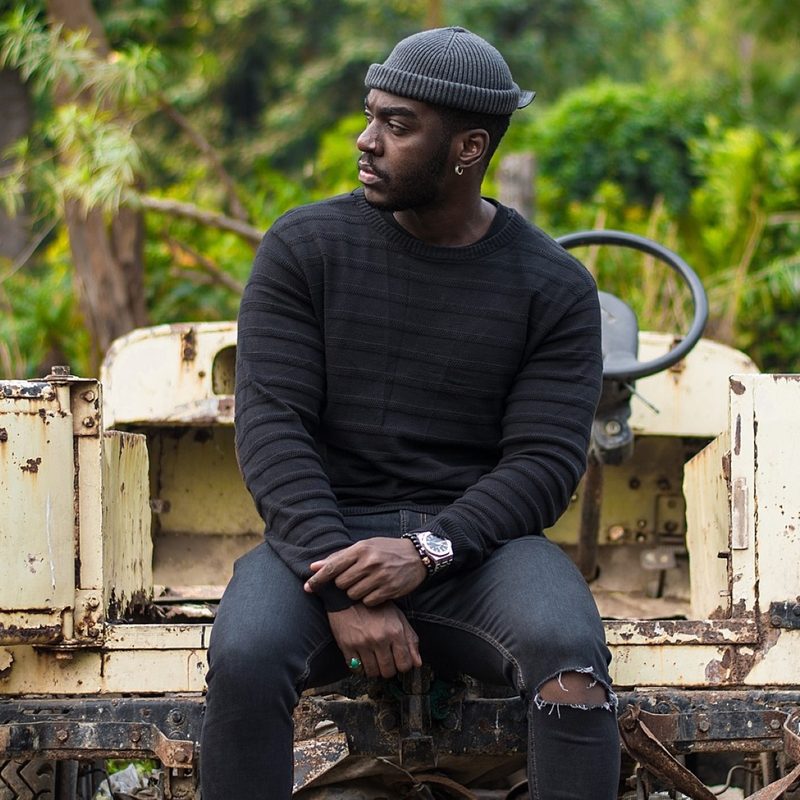 Man in black jeans, sweater, and hat