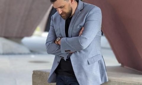 Man in blazer and jeans looking down