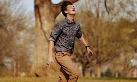 Man in brown pants and tucked in patterned shirt