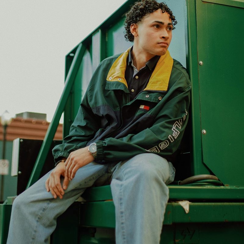 Man in jeans sitting on a dumpster