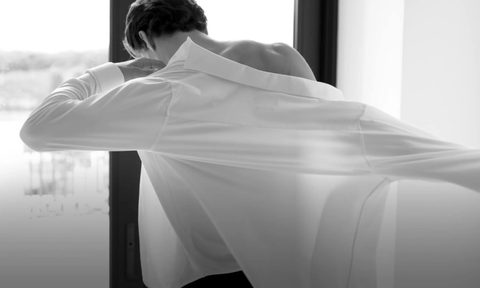 Man putting on a dress shirt