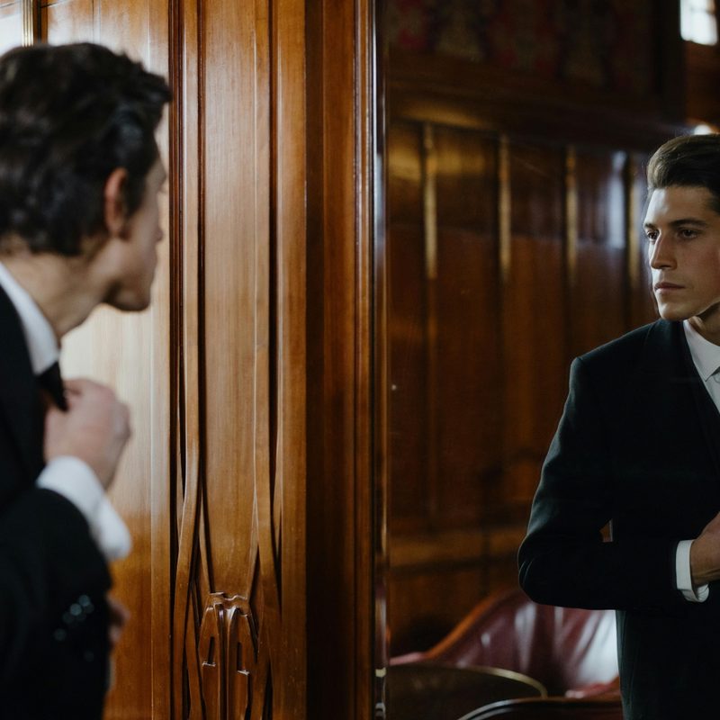 Man straightening his tie in the mirror